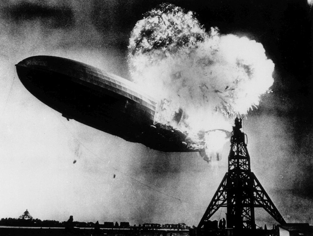 ADVANCE FOR SUNDAY AUG. 22--FILE--This photo, taken during the initial explosion of the Hindenburg, shows the 804-foot German zeppelin just before subsequent explosions sent the ship crashing to the ground at Lakehurst Naval Air Station in Lakehurst, N.J., May 6, 1937. The roaring flames silhouette two men, at right atop the mooring mast, dangerously close to the blasts. The scene stimulated NBC radio broadcaster Herbert Morrison to give a memorable and highly emotion account of the disaster. (AP Photo/Philadelphia Public Ledger, HO)