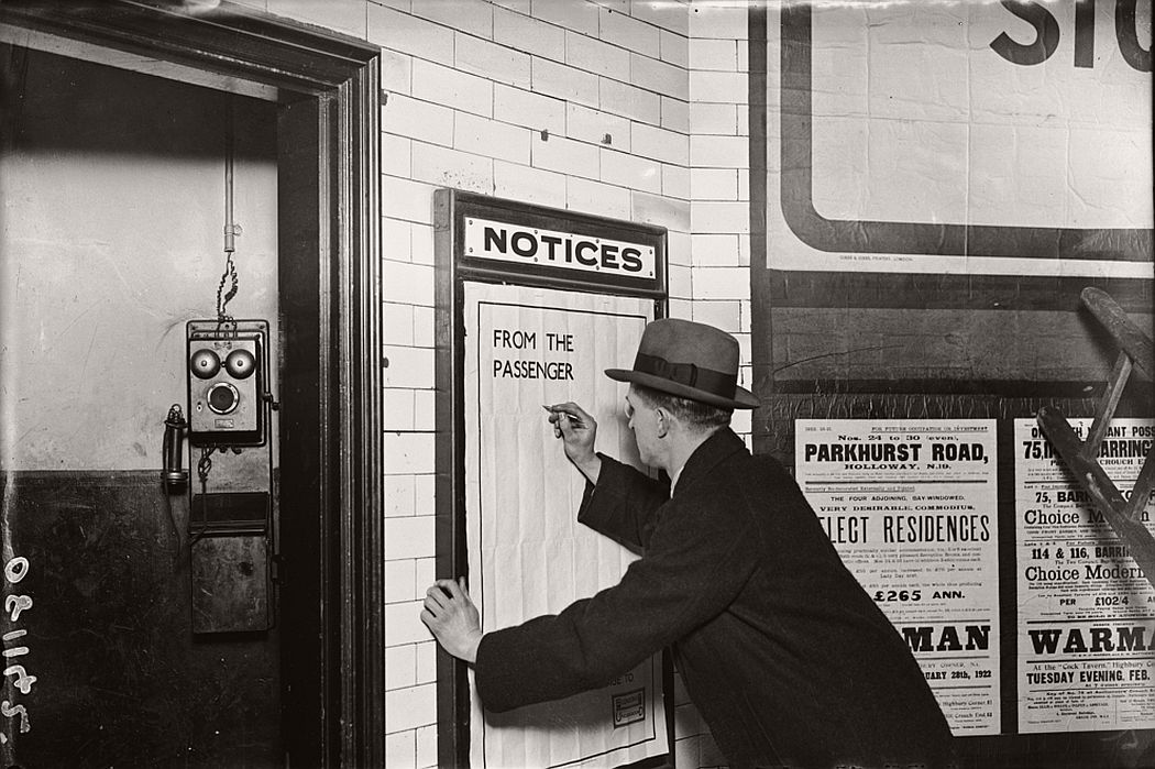 A man writing on a complaints poster, 1922.