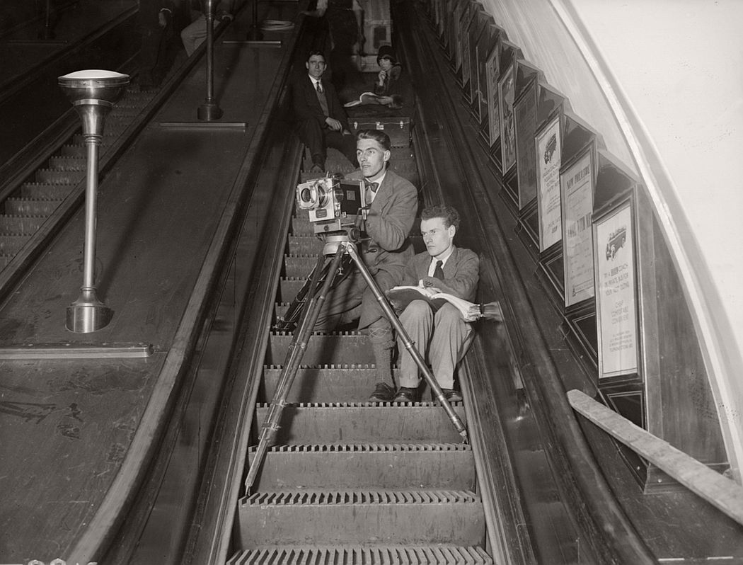 British director Anthony Asquith (1902-1968), right, directing his new film 'Underground' from an escalator on the London underground, May 1928.