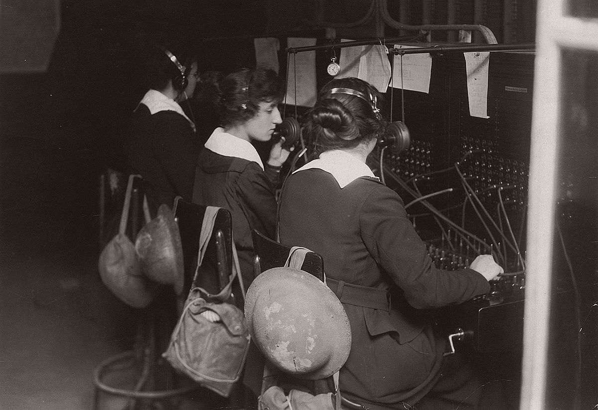   U.S. Signal Corps telephone operators in Advance Sector, 3 km from the trenches in France. The women were part of the Signal Corps Female Telephone Operators Unit and were also known as Hello Girls. Women have helmets and gas masks in bags on back of chairs. # National World War I Museum, Kansas City, Missouri, USA
