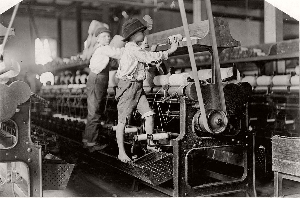 Boys climb up on the spinning frame to mend the broken threads and put back the empty bobbins, Macon, Georgia, 19 january 1909