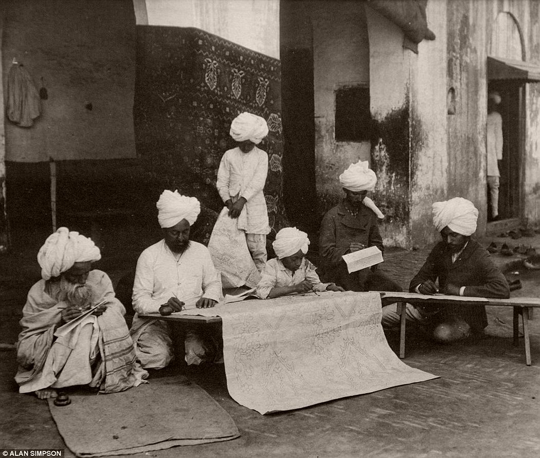 A group of men draw carpet designs.