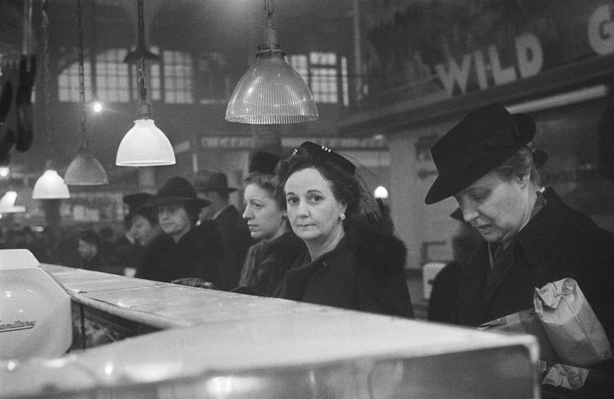 Roman Vishniac, [Customers waiting in line at a butcher’s counter during wartime rationing, Washington Market, New York], 1941–44. Ink-jet print. © Mara Vishniac Kohn, courtesy International Center of Photography.