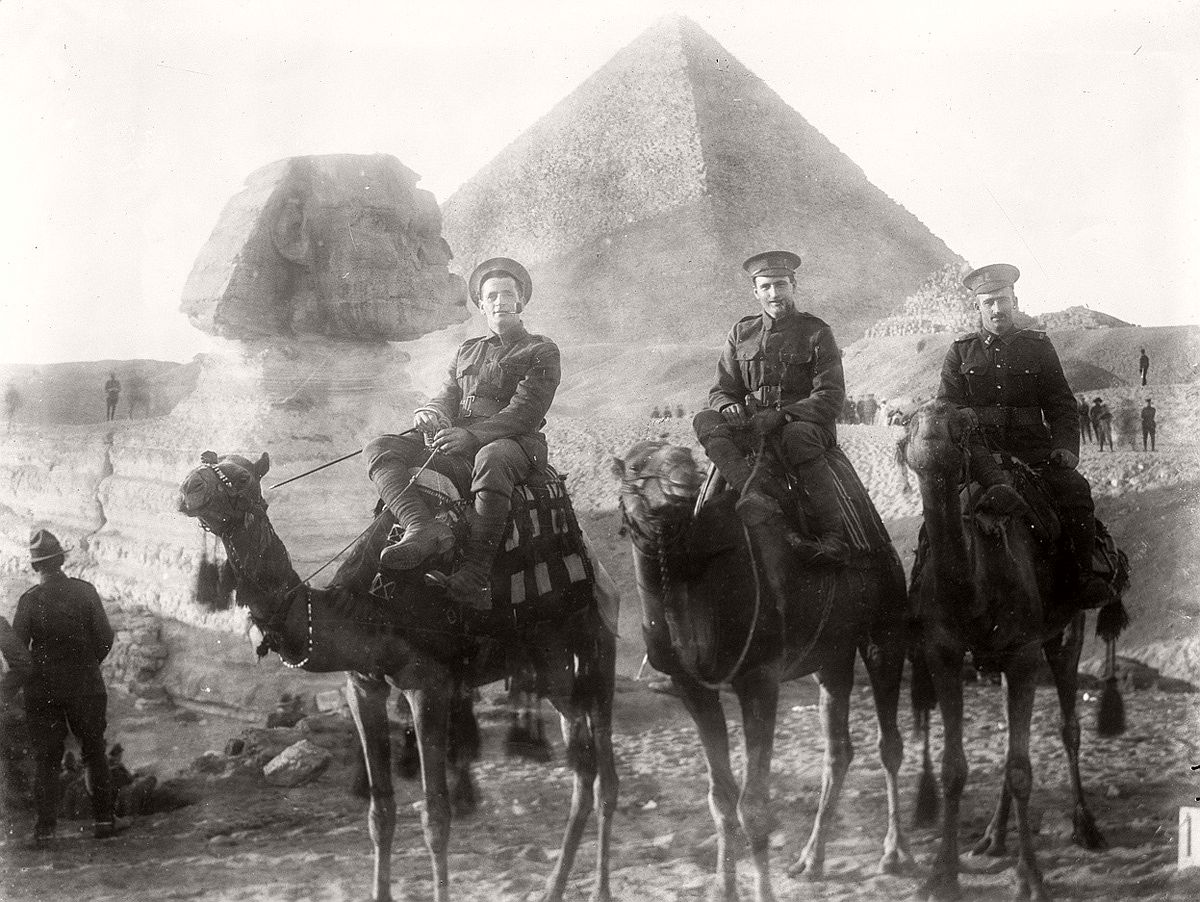   Three unidentified New Zealand servicemen riding camels during World War I, the Sphinx and a pyramid in the background. # James McAllister / National Library of New Zealand