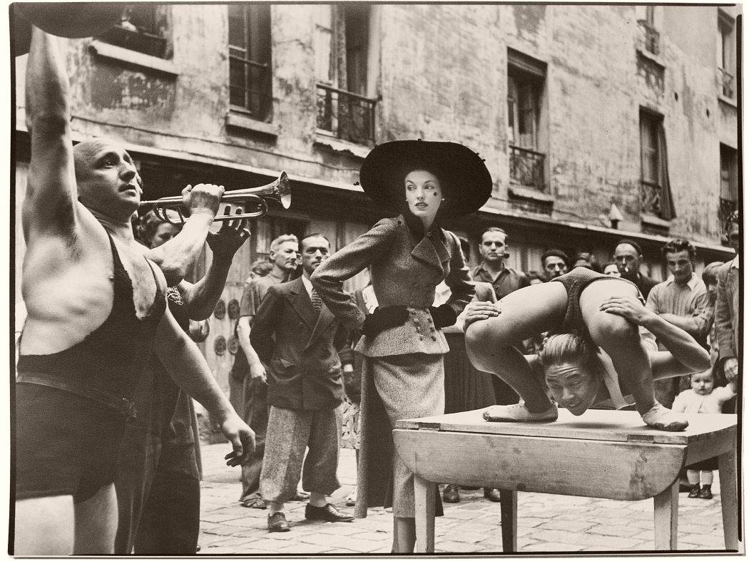 Elise Daniels with street performers, Suit by Balenciaga, Le Marais, Paris, August, 1948 by Richard Avedon