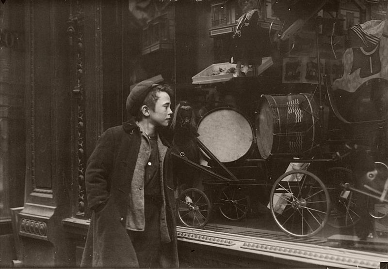 Boy looking at Xmas toys in shop window, 1900.
