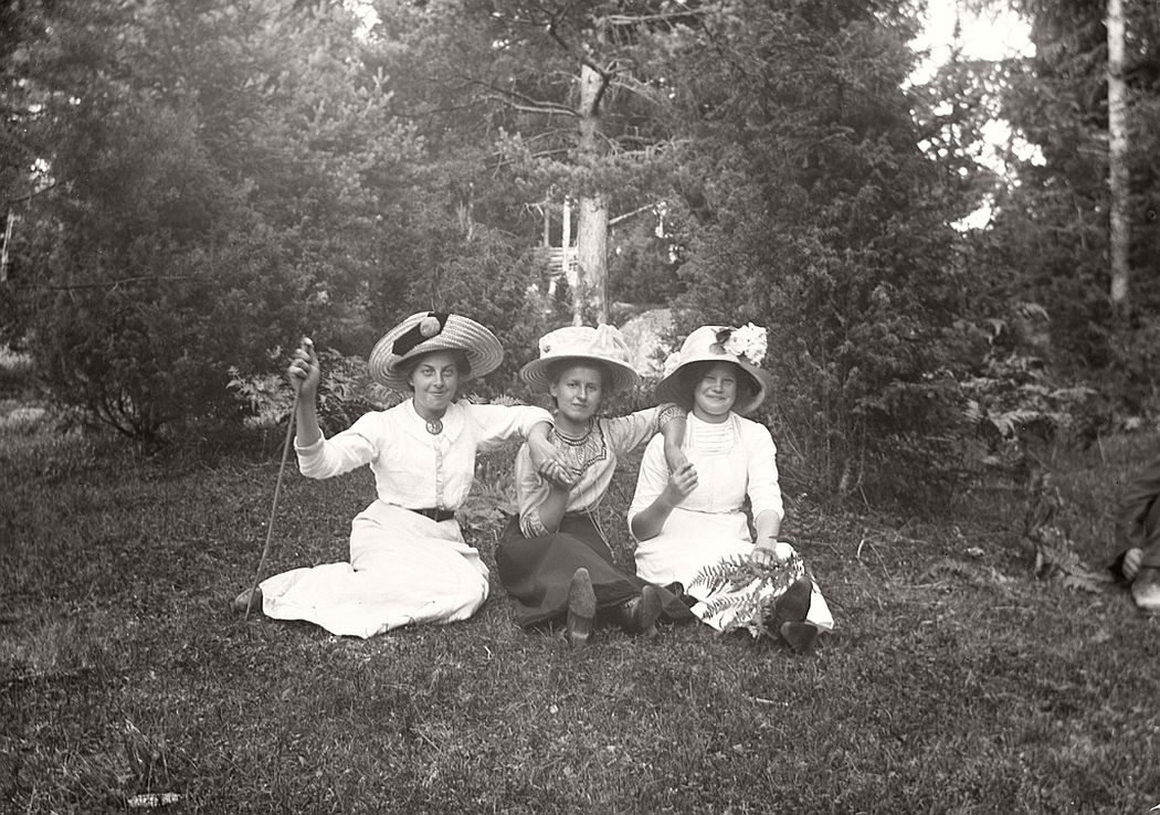 Three happy women sitting on the grass.