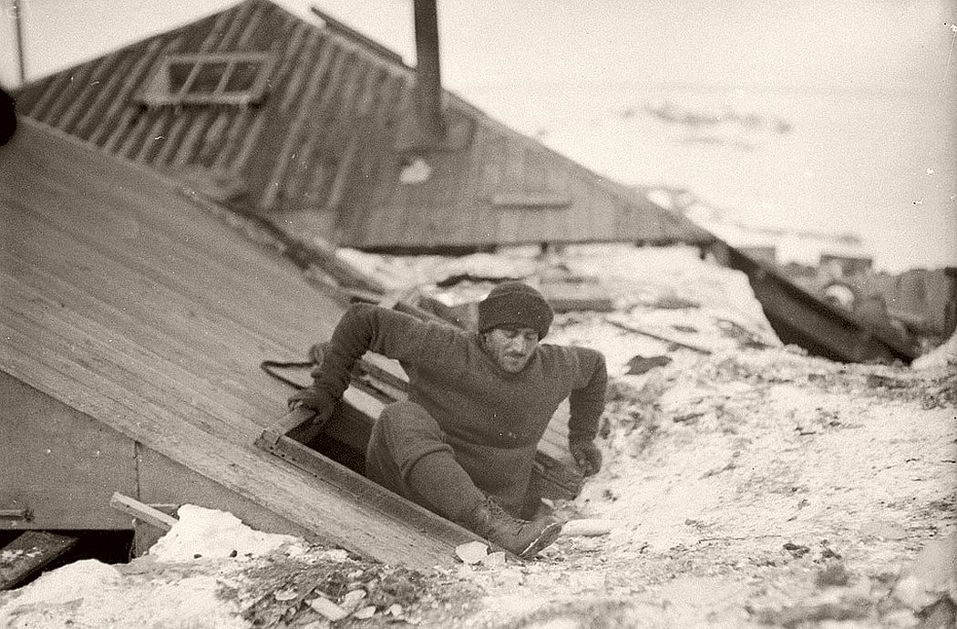 Mertz leaving the hut by the trapdoor on the verandah roof, circa 1912
