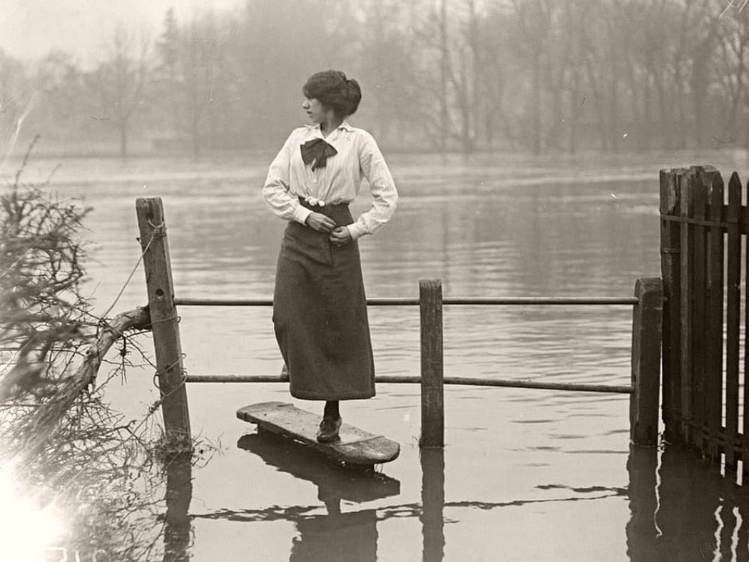 A woman crossing a stile after the flooding in the Thames Valley, December 1915.