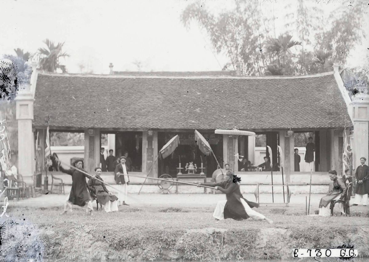 Two people fight, using long wooden poles as lances, as part of Tet celebrations in Hanoi, 1929. This sport, known as la lutte à la lance in French and roi truong in Vietnamese, was a traditional one engaged in during festivals in Vietnam. Combatants score points by hitting their opponents with wooden lances wrapped in fabric at one end, in various body parts. Any player who lets go of his lance automatically loses the match.