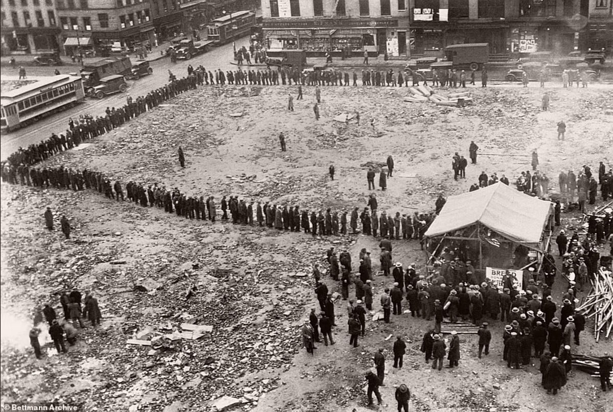 Despite heavy rainfall, the unemployed wait in bread lines on the corner of Chrystie and Grand Street in the Lower East Side. A few blocks away stood New York City's largest shantytown, known as 'Hardlucksville,' with upwards of 80 shacks that housed 450 men